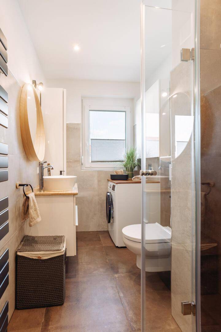 Modernes Badezimmer mit begehbarer Dusche, Waschmaschine und Fenster für Tageslicht.