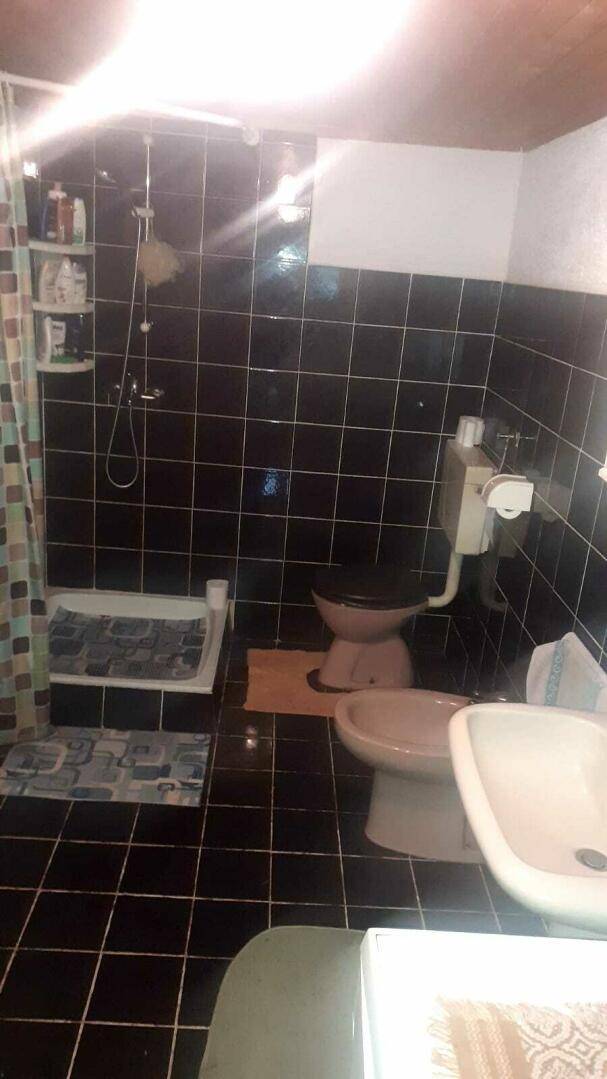 Badezimmer mit schwarzen Fliesen, einer Dusche und einem Waschbecken in traditionellem Stil.