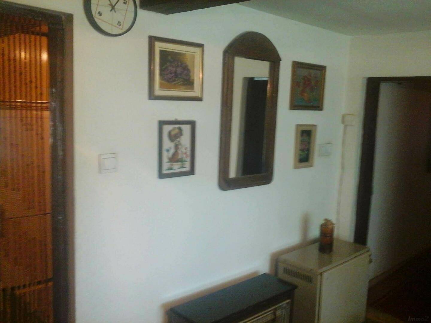 Flur mit weiß gestrichenen Wänden, Holzbalken an der Decke und verschiedenen Bildern an der Wand.