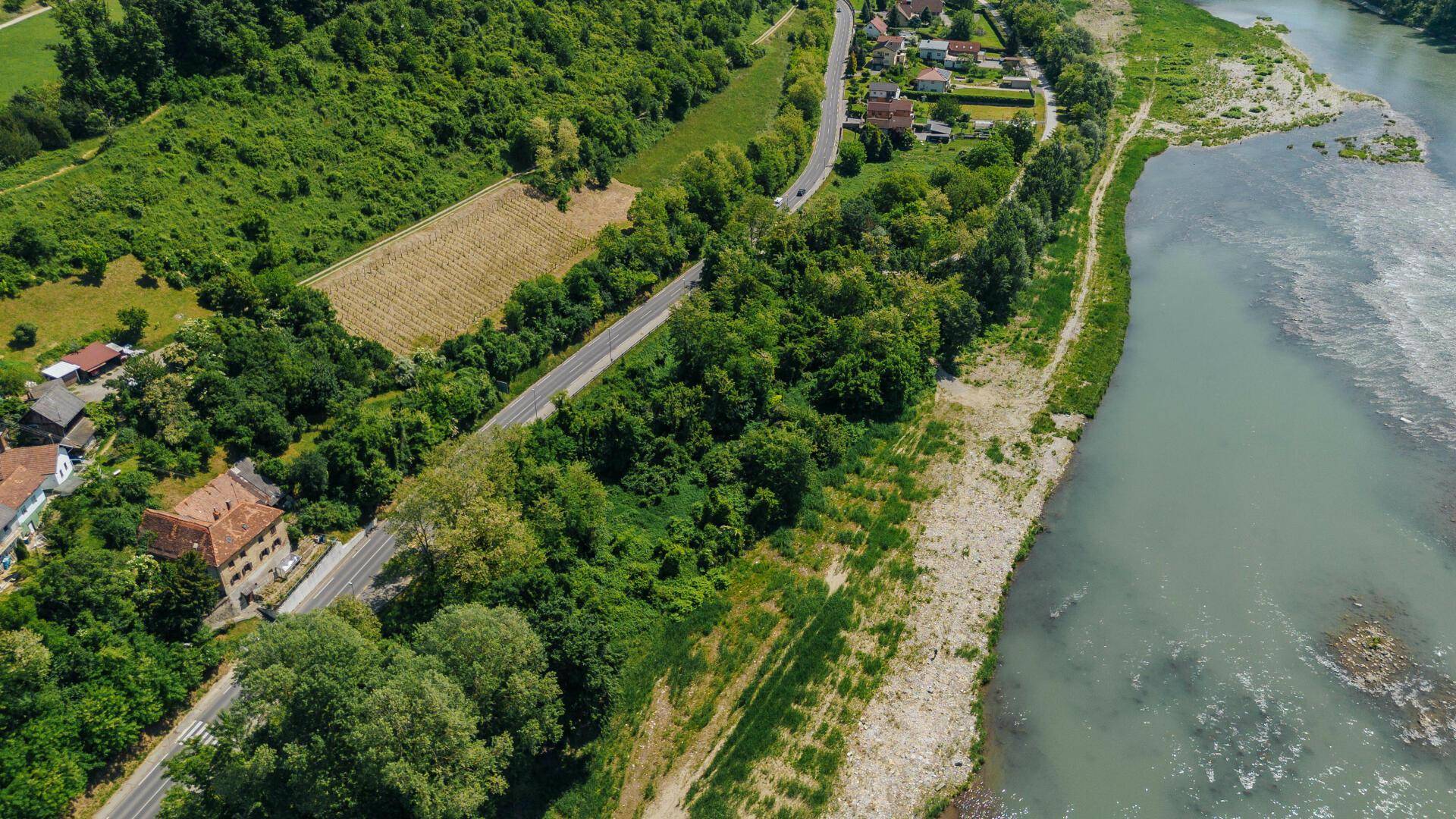 Nahaufnahme einer Flusslandschaft mit Straße, grünen Hügeln, Häusern und einem Weinberg.