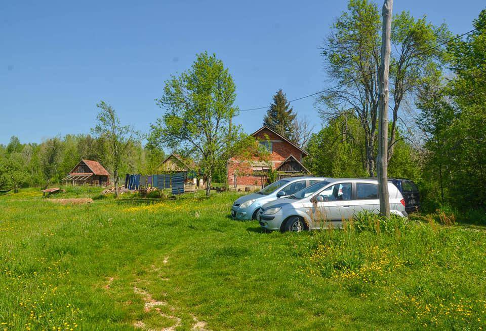 Mehrere Autos parken auf einer grünen Wiese vor dem Anwesen mit weiteren Gebäuden im Hintergrund.