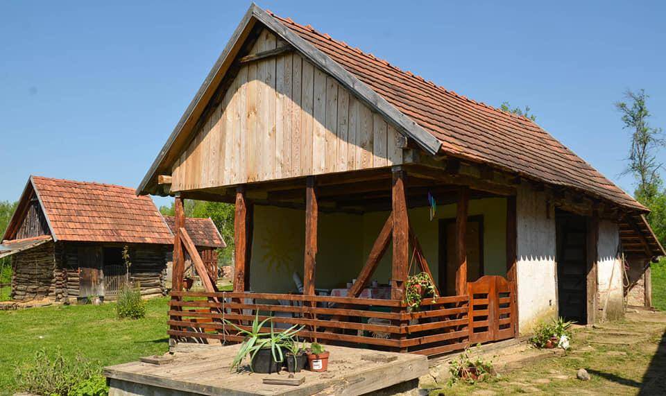 Rustikales Holzhaus mit einer überdachten Veranda und traditionellem Ziegeldach in ländlicher Umgebung.