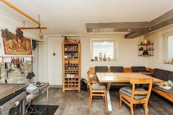 Rustikaler Essbereich mit Holztisch, Sitzbank und Fliesenboden, angrenzend an die Küche.