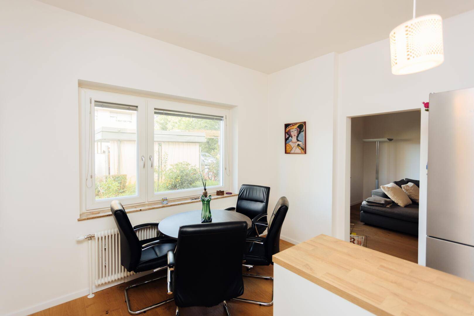 Essbereich in der Küche mit rundem Tisch, schwarzen Stühlen und Fensterblick.