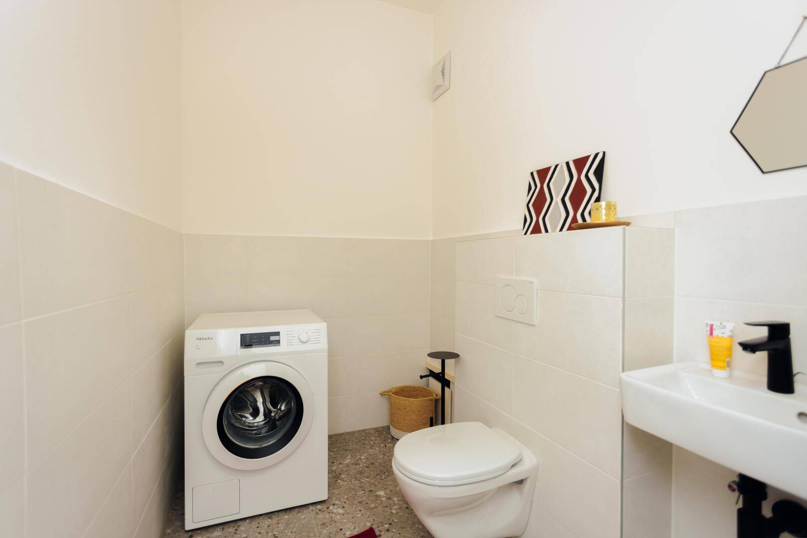 Kleiner Raum mit Toilette, Waschmaschine und Waschbecken.