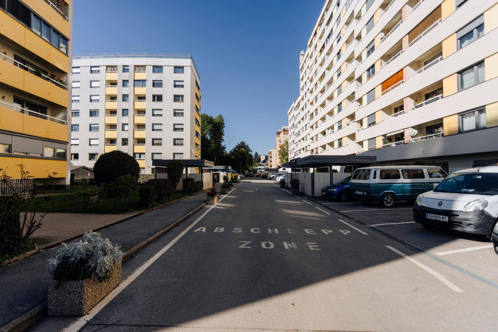 Wohngebäude in einer städtischen Umgebung mit Parkplätzen und Bäumen.