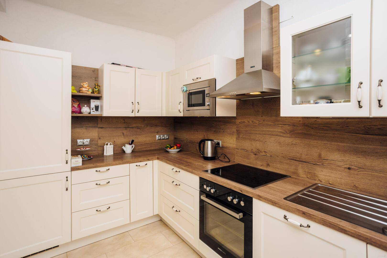 Funktionale Küche mit weißen Fronten, Holzdetails und modernen Einbaugeräten.