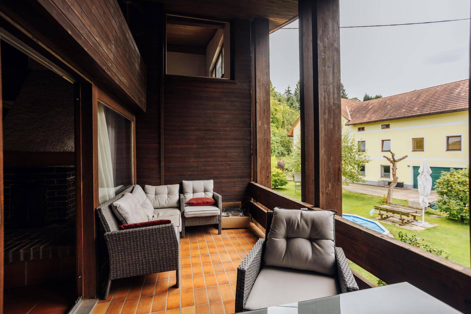 Geräumiger Balkon mit Lounge-Möbeln und Blick auf den Gartenbereich mit Pool.