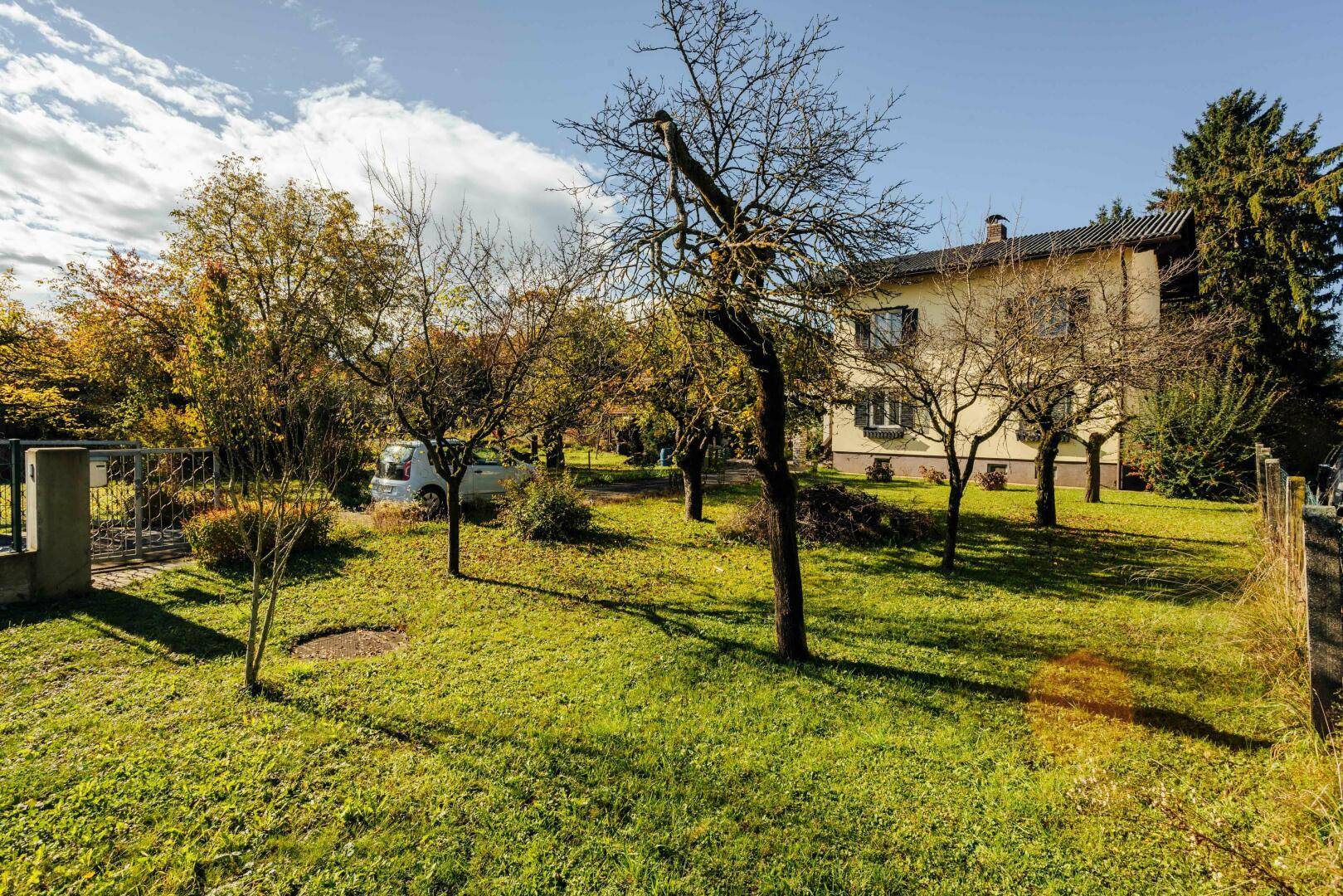 Weitläufiger Garten mit Rasen und Obstbäumen, das Haupthaus ist im Hintergrund sichtbar.