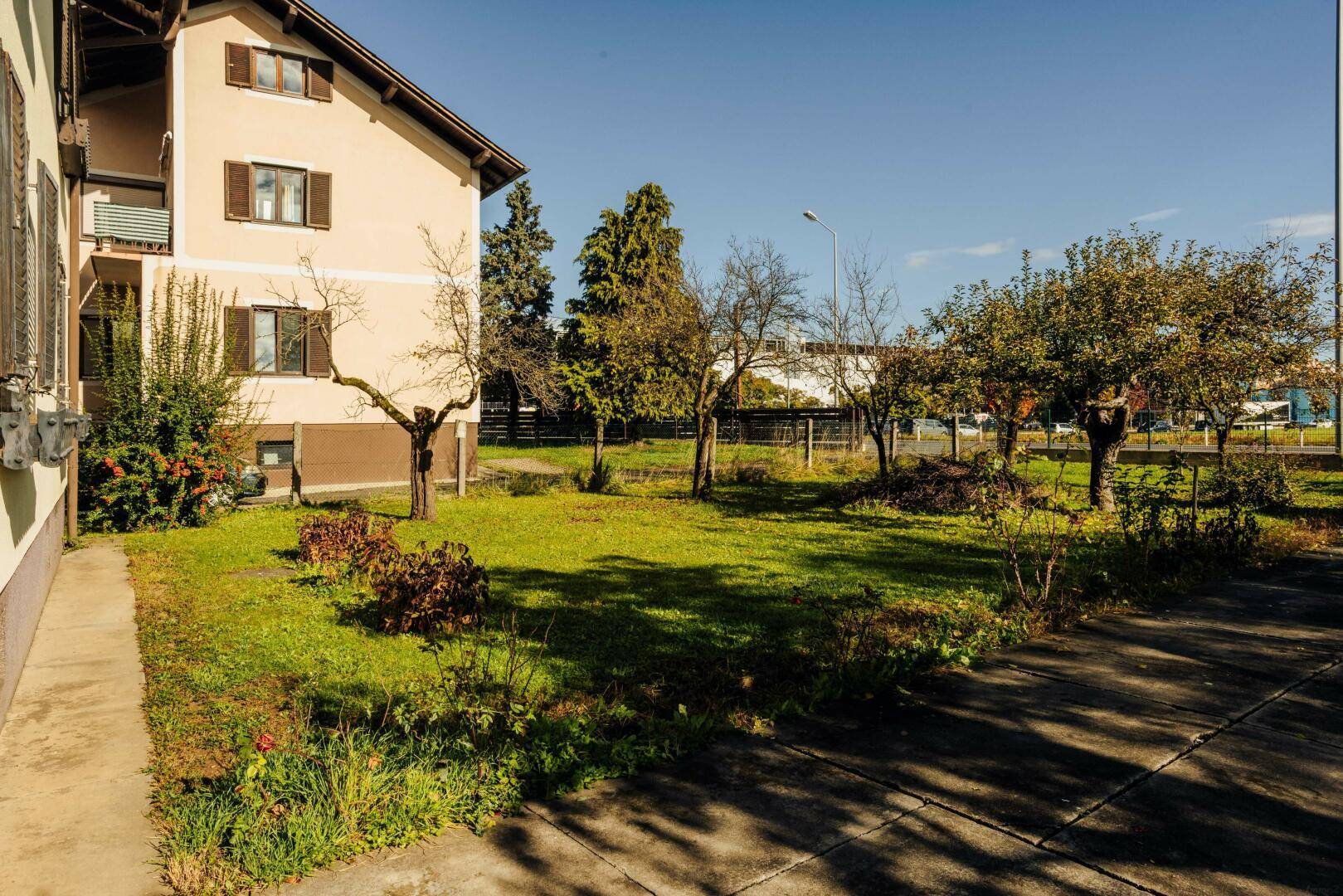 Seitenansicht des Hauses mit Rasenfläche und Bäumen, die eine grüne Umgebung schaffen.