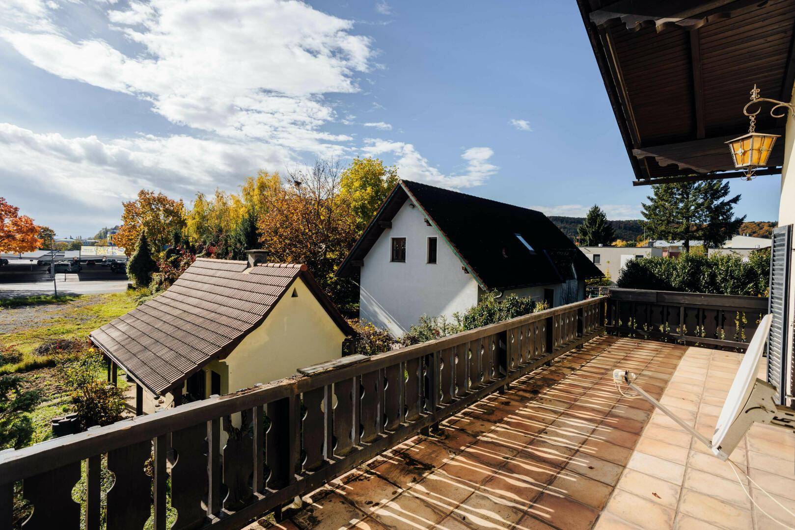 Geräumiger Balkon mit Fliesenboden, Holzgeländer und weitem Blick auf die Umgebung.