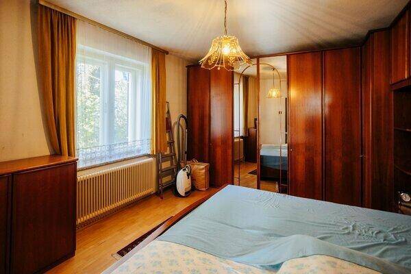 Schlafzimmer mit Parkettboden, großem Kleiderschrank mit Spiegeltüren und Fensterblick.