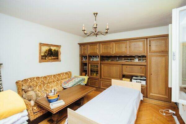 Helles Schlafzimmer mit Einzelbett, Holzmöbeln und einem Sofa, ideal als Gästezimmer.