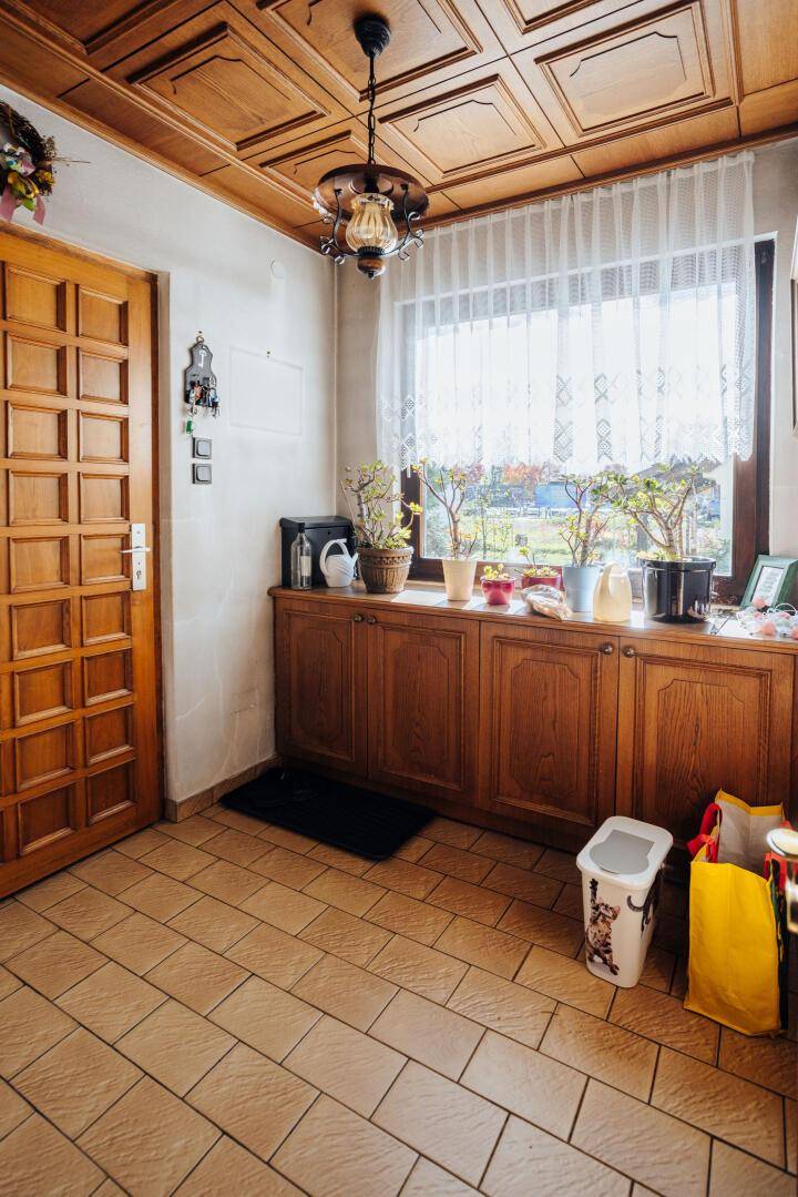 Heller Eingangsbereich mit Holztür, gefliestem Boden und einer Holzdecke.