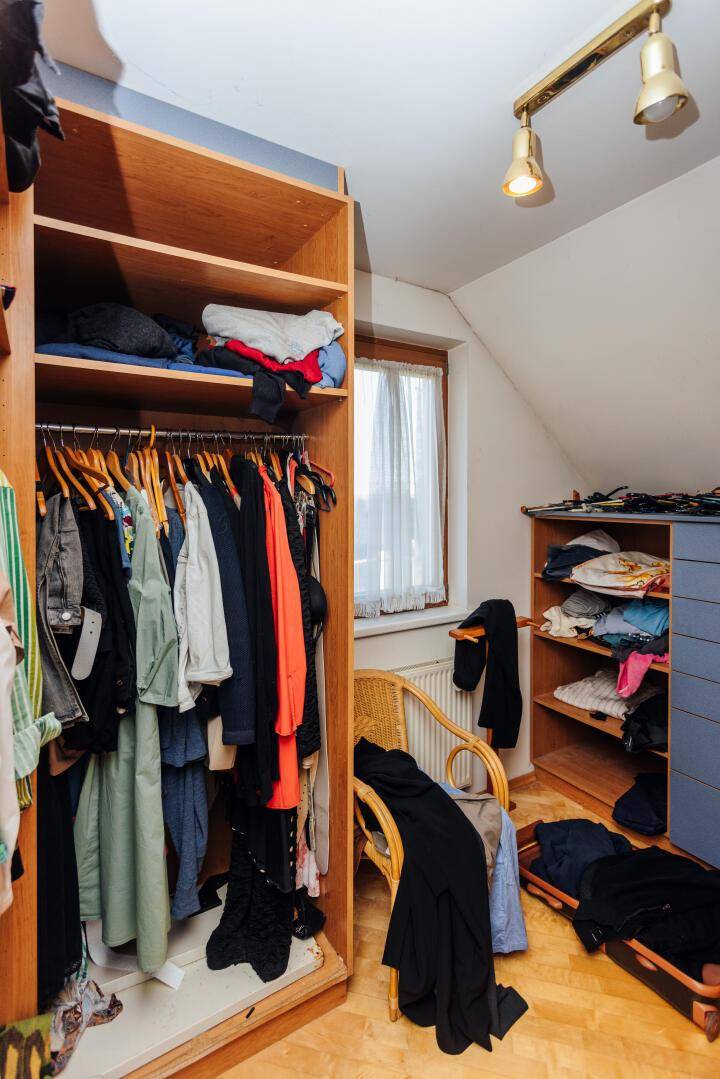 Begehbarer Kleiderschrank mit Regalen, Kleiderstangen und Fenster für Tageslicht.