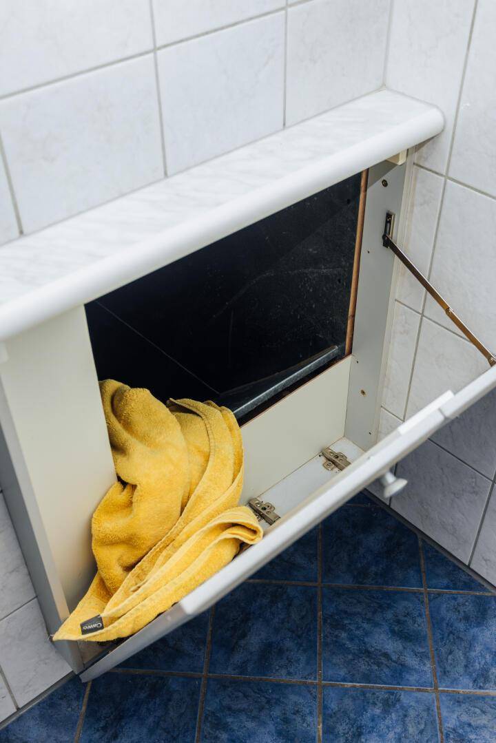 Detailansicht eines Badezimmerschranks mit Handtuch und blauen Bodenfliesen.