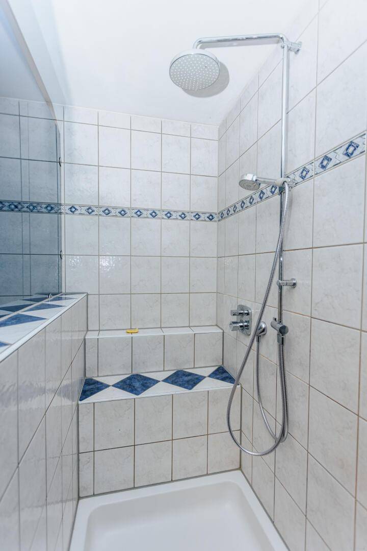 Gefliestes Badezimmer mit Duschkabine und blauen Akzenten.
