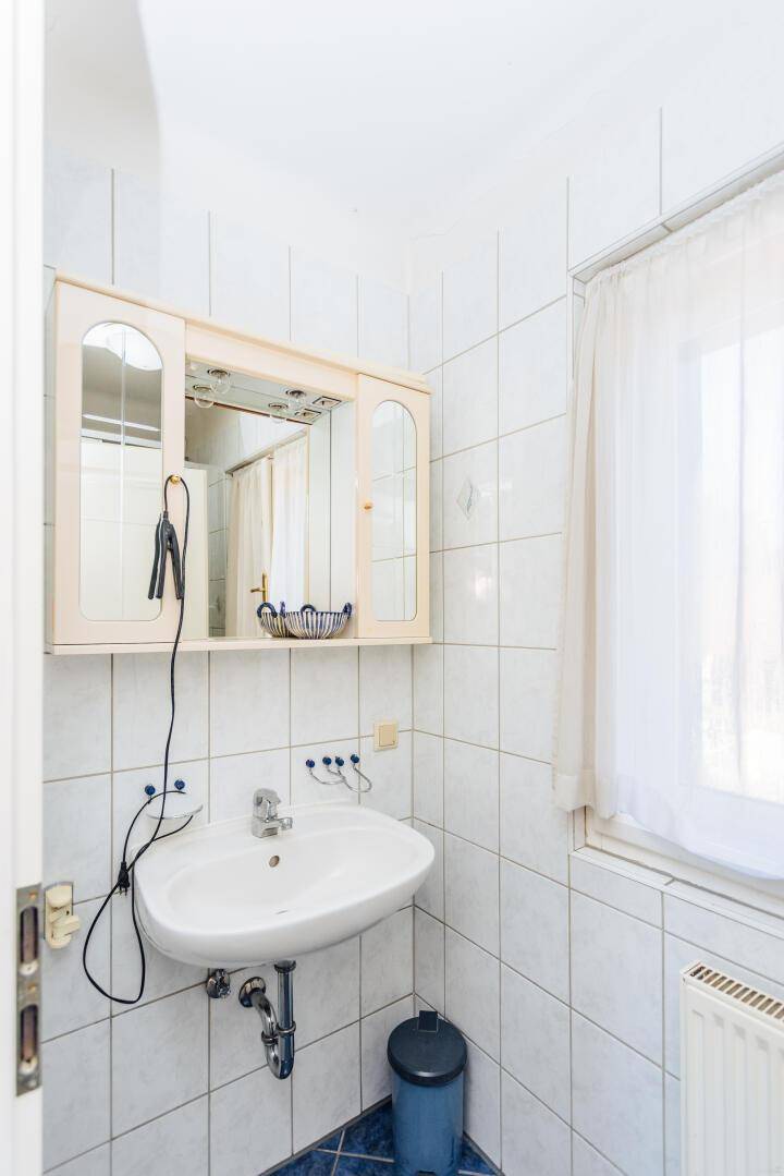 Kleines Badezimmer mit Waschbecken, Spiegelschrank und Fenster.