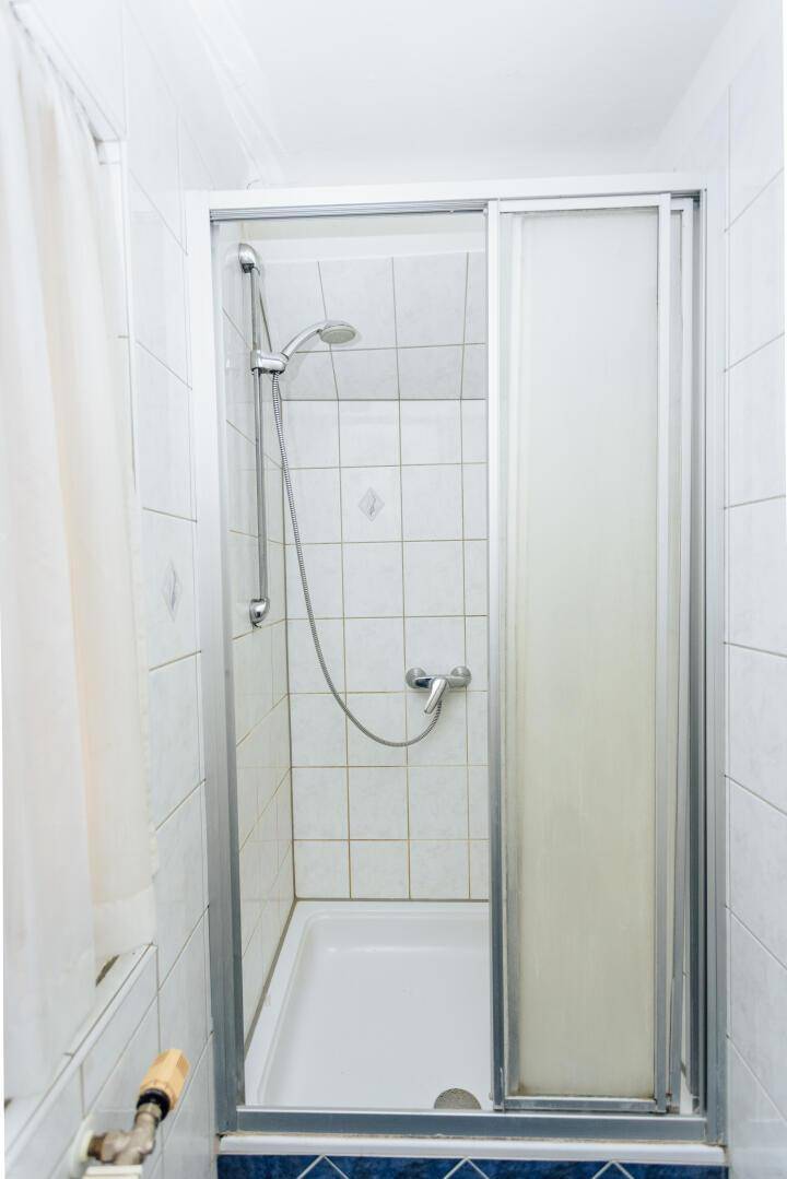 Duschkabine mit Glasschiebetür und weißen Fliesen in einem Badezimmer.