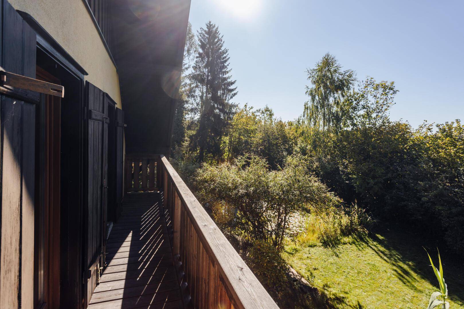 Holzbalkon mit Geländer und weitem Blick über die grüne Umgebung.