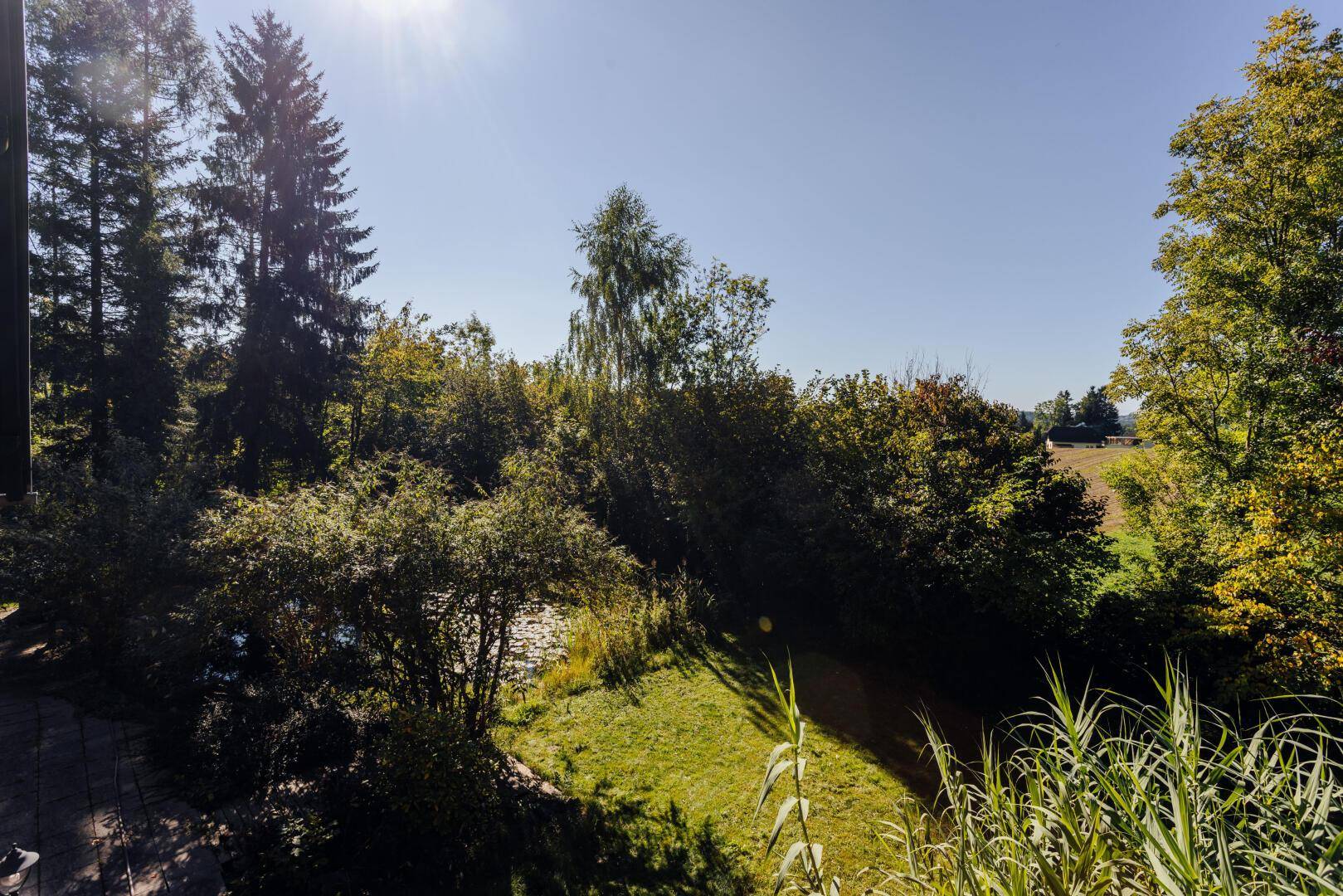 Sonniger Ausblick vom Balkon auf den Garten und die weite Landschaft.