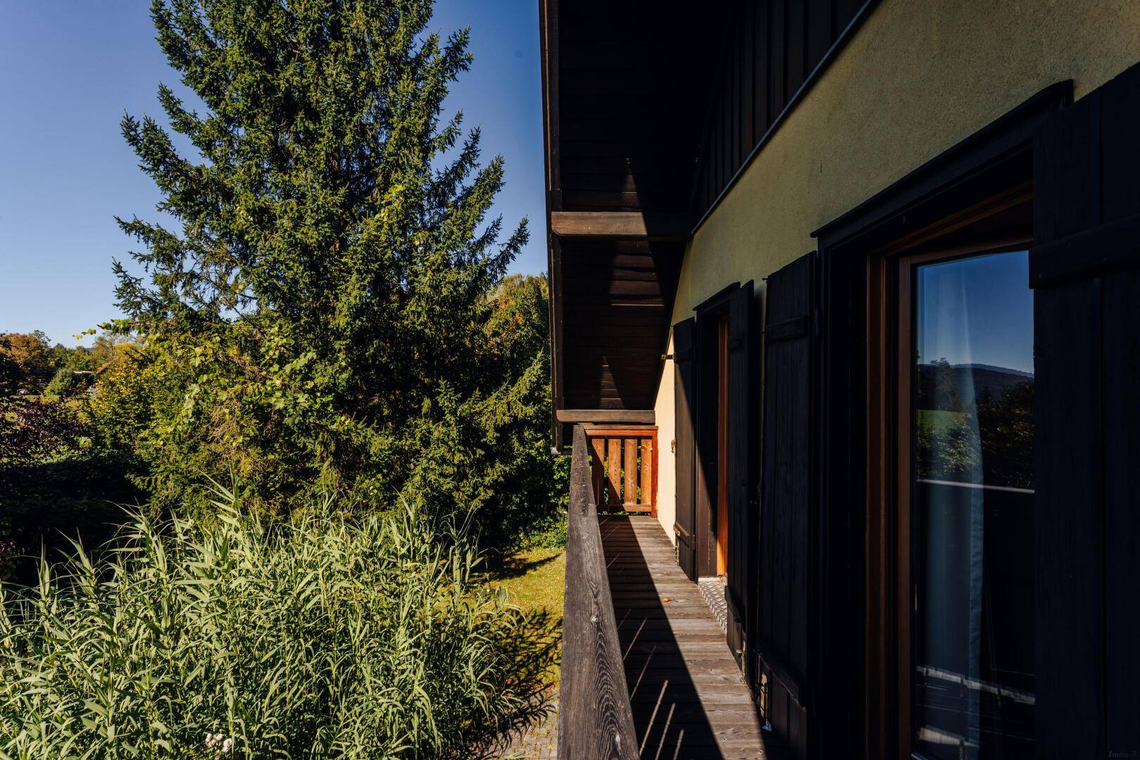 Langer Holzbalkon mit Blick auf die umliegende grüne Landschaft.