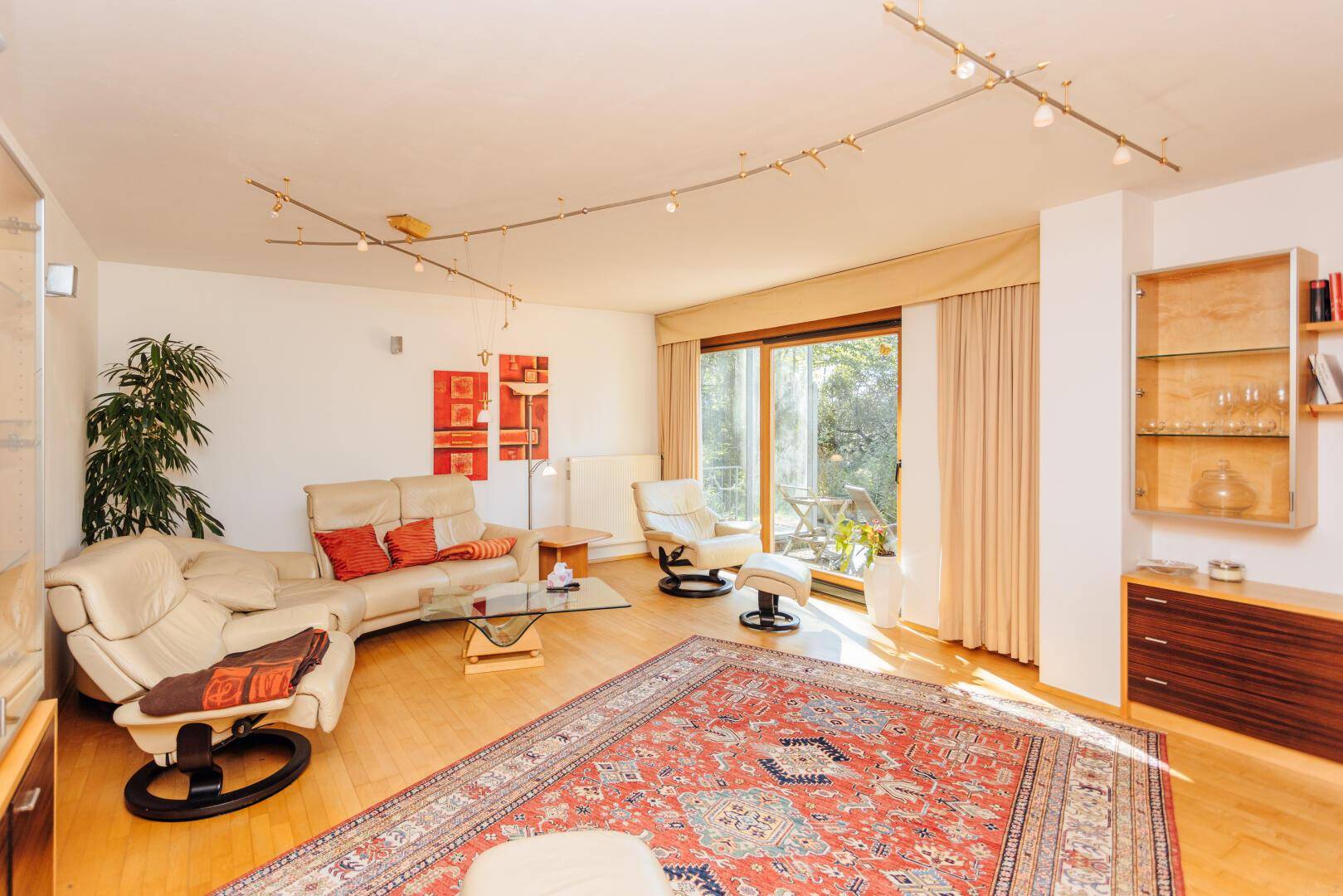 Helles Wohnzimmer mit Parkettboden, bequemen Sofas und Zugang zur Terrasse.