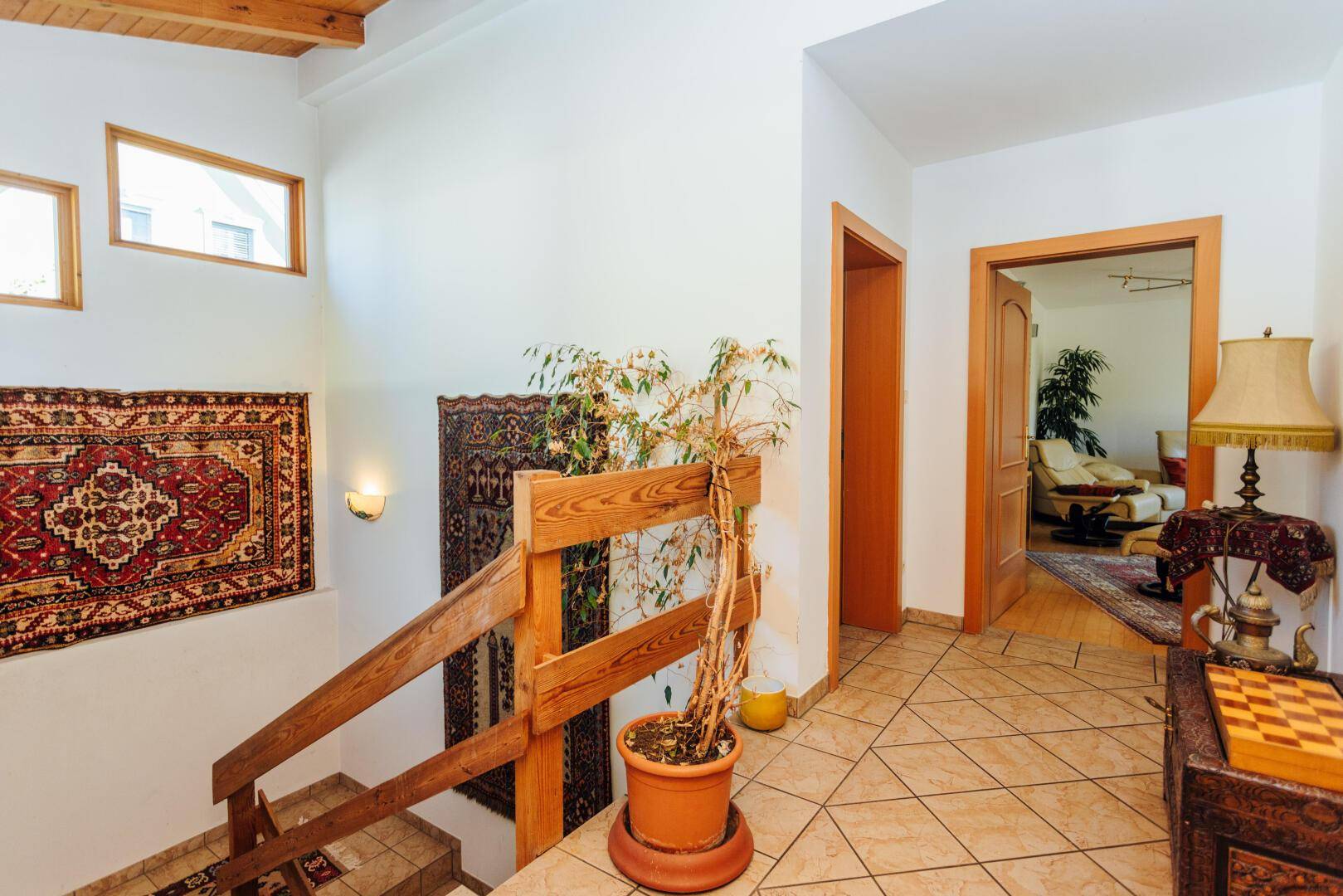Eingangsbereich mit Treppe, Fliesenboden und dekorativen Teppichen.