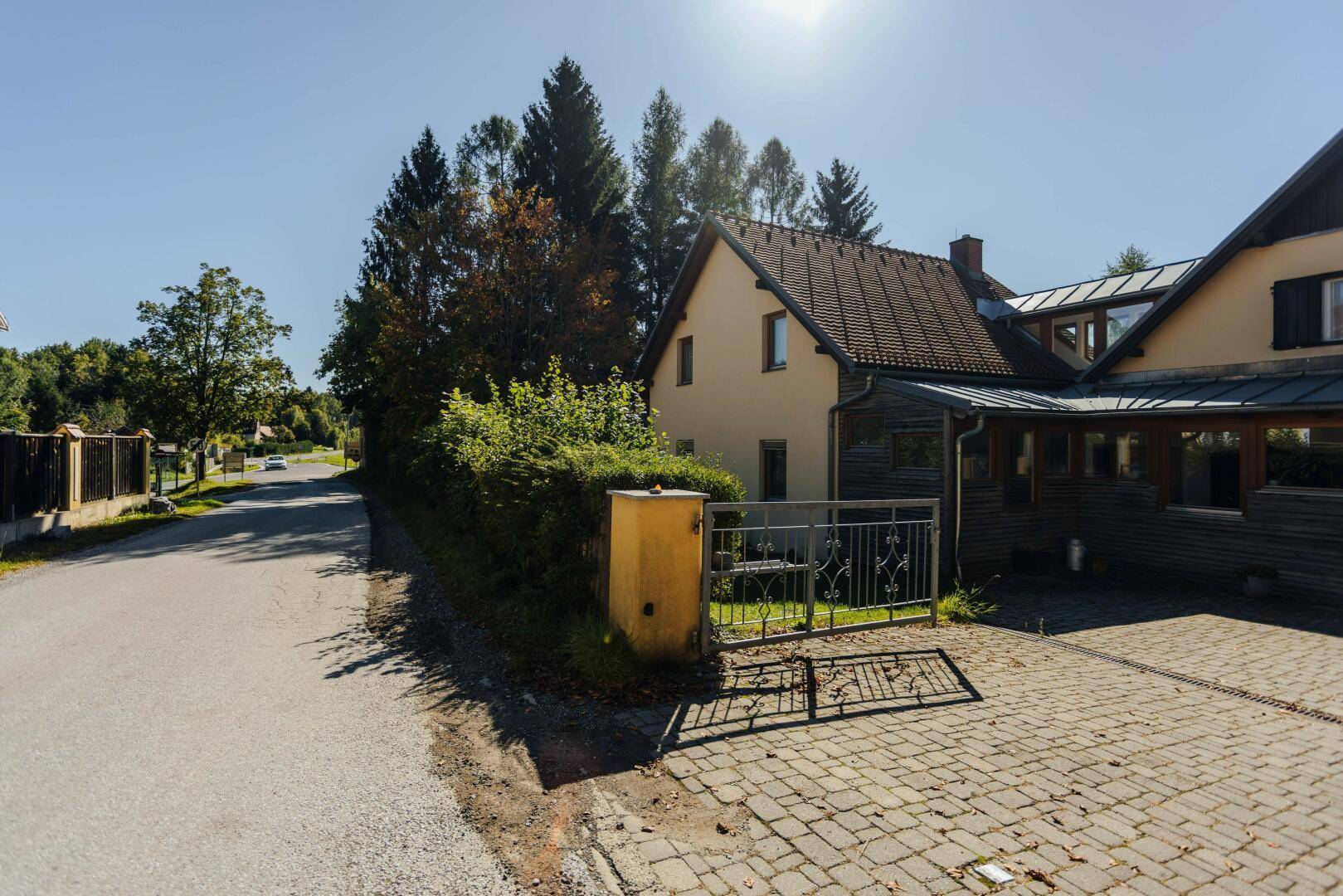 Zufahrt zum Anwesen mit gepflastertem Bereich und Blick auf die ruhige Landstraße.