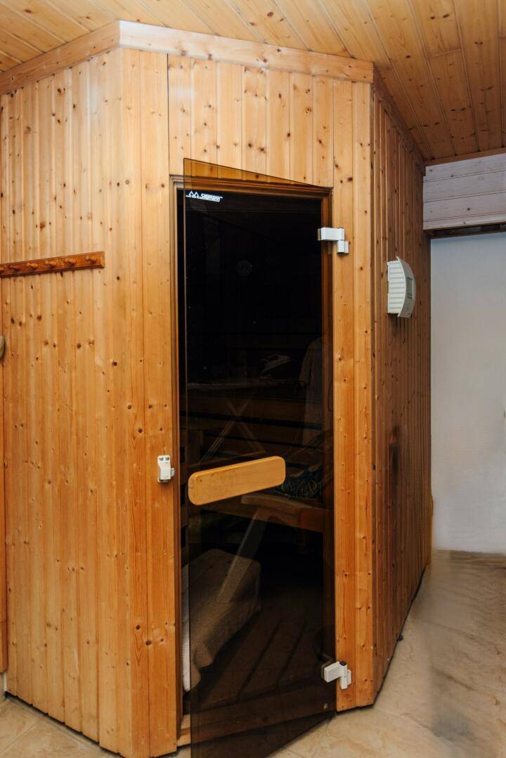 Holzvertäfelte Sauna mit Glastür und charakteristischen Bänken für Entspannung.