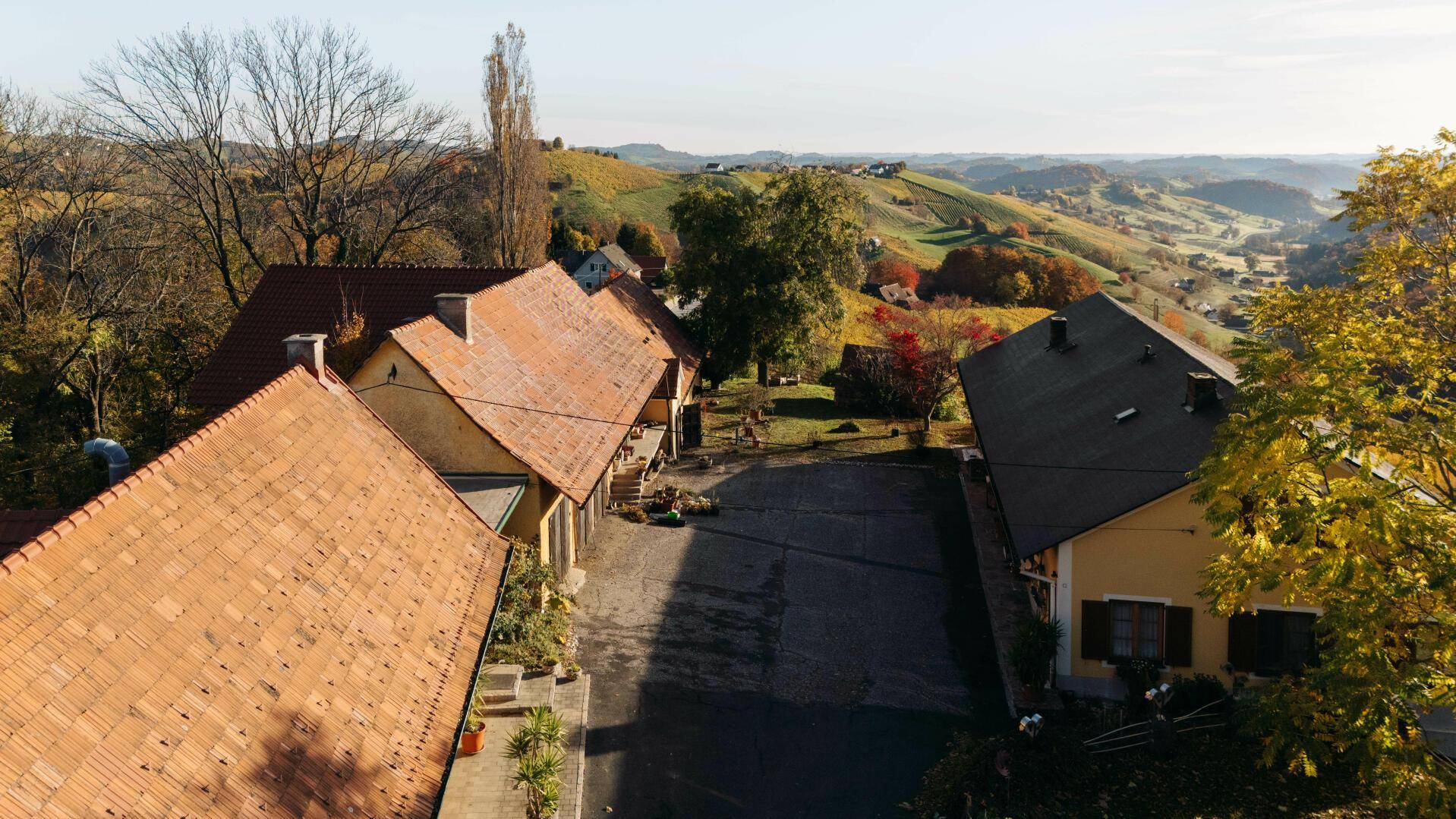 Blick auf den Zufahrtsweg zwischen den Gebäuden des Anwesens, mit Weinbergen in der Ferne.