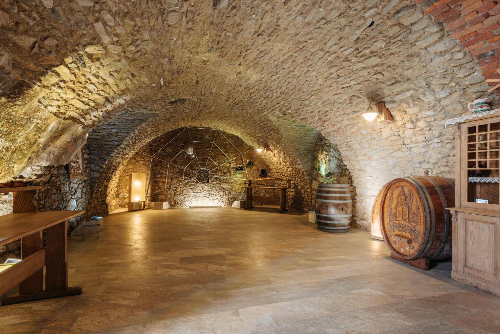 Alter Weinkeller mit Steinmauern, Gewölbedecke und Holzfässern, ideal für Weinlagerung.