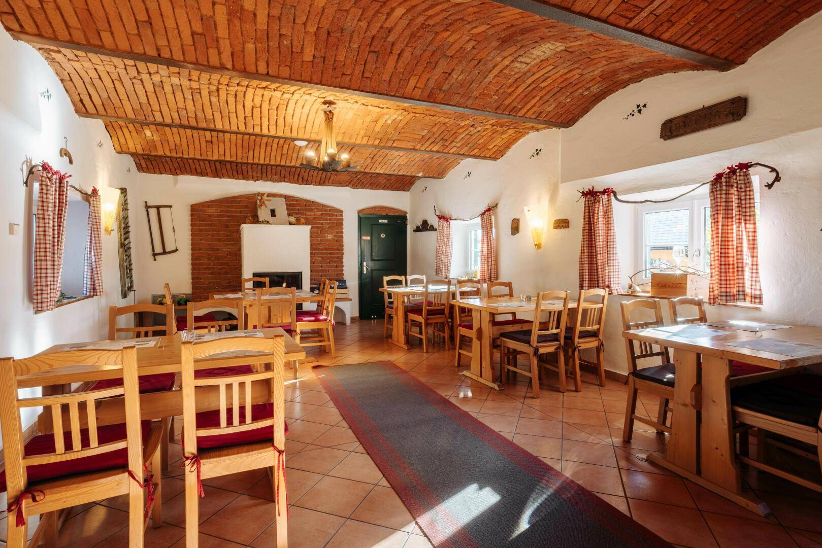 Rustikaler Speisesaal mit Ziegelgewölbedecke, Holztischen und traditioneller Einrichtung.