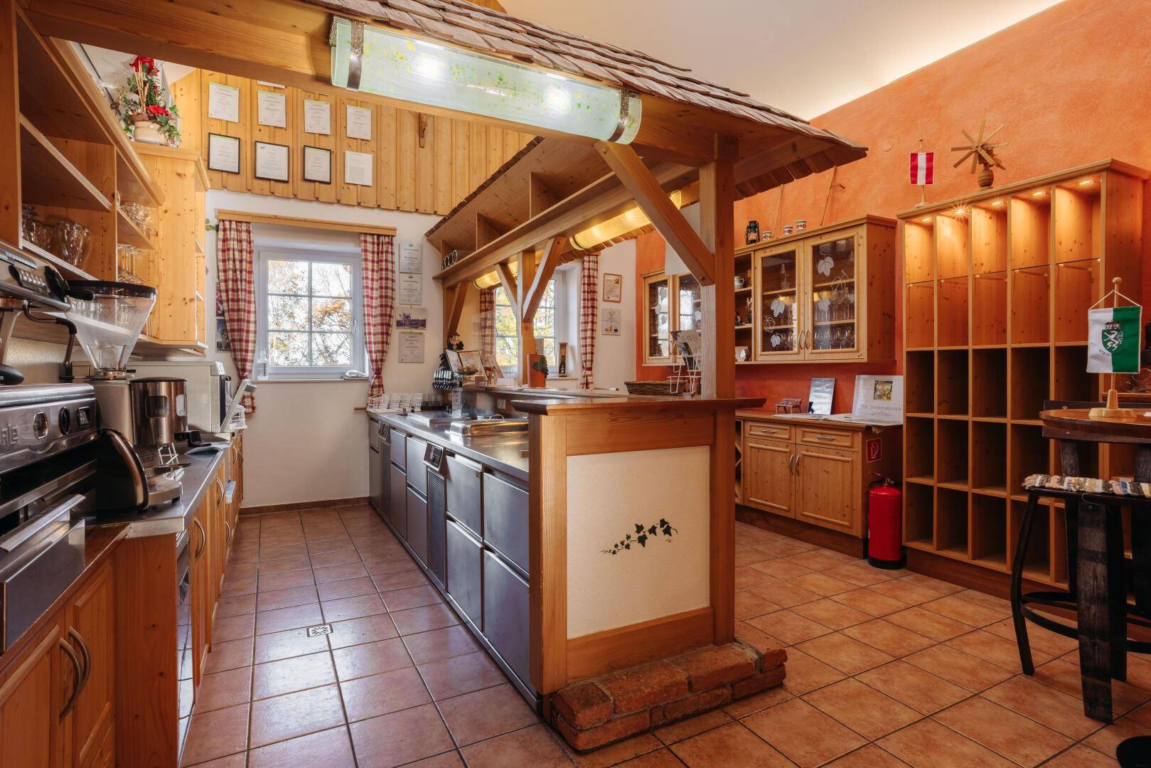 Rustikale Küche mit Holzmöbeln, Fliesenboden und einer Theke unter einem Holzdach.