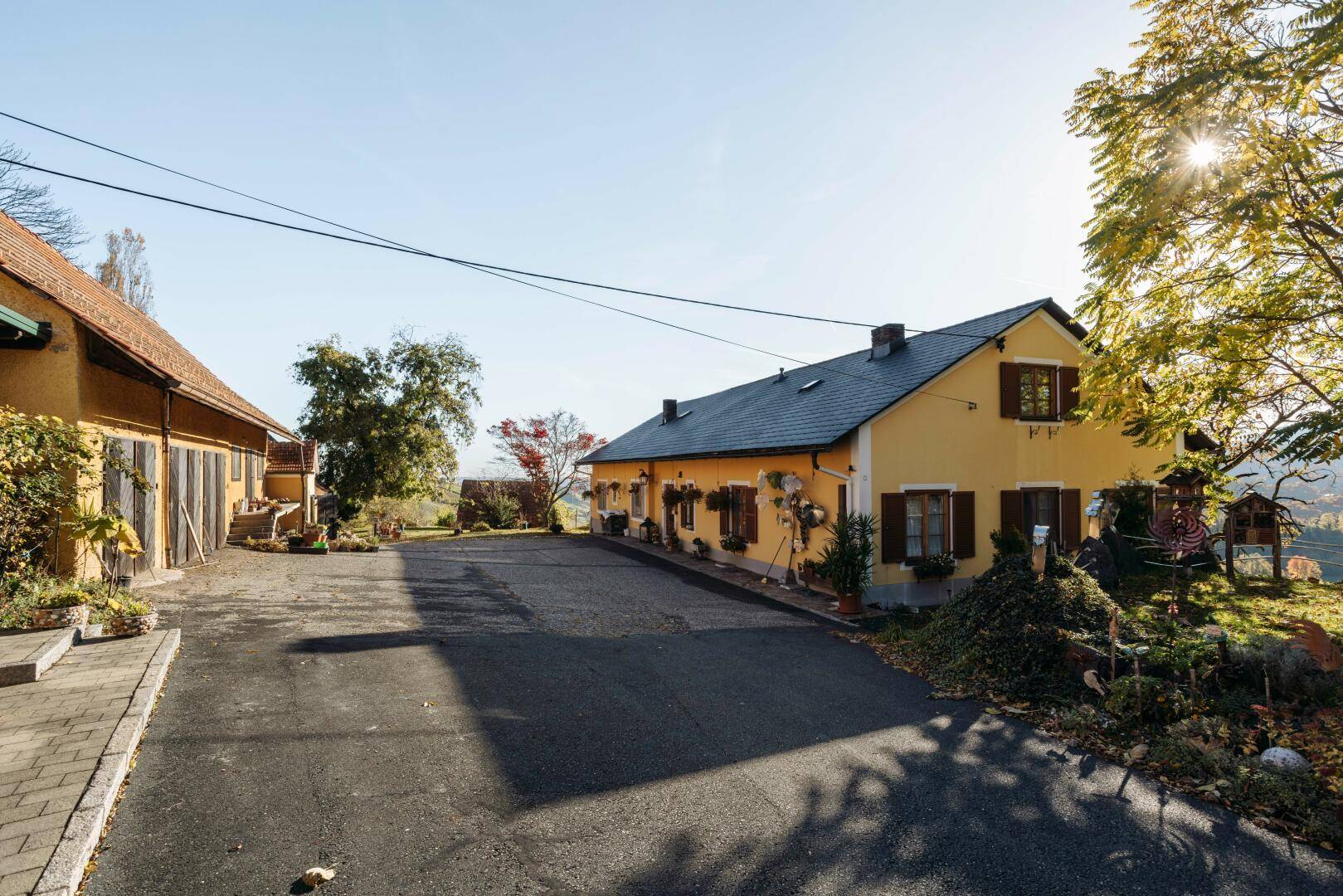 Gebäudekomplex mit gelben Fassaden und dunklen Dächern, umgeben von grüner Landschaft.