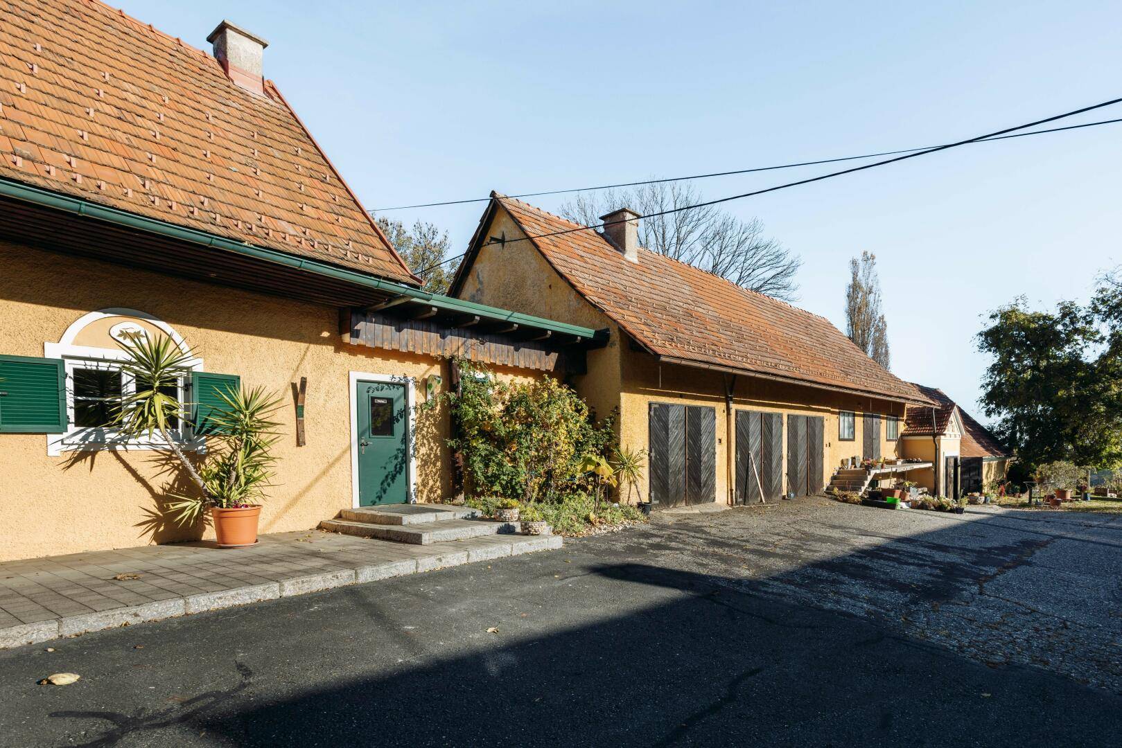 Mehrere traditionelle Gebäude mit Ziegeldächern und einer Zufahrt in ländlicher Umgebung.