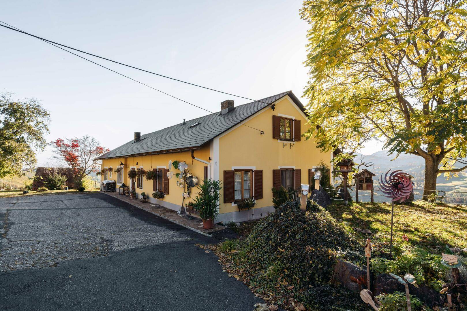 Traditionelles gelbes Gebäude mit braunen Fensterläden und einem gepflegten Vorgarten.