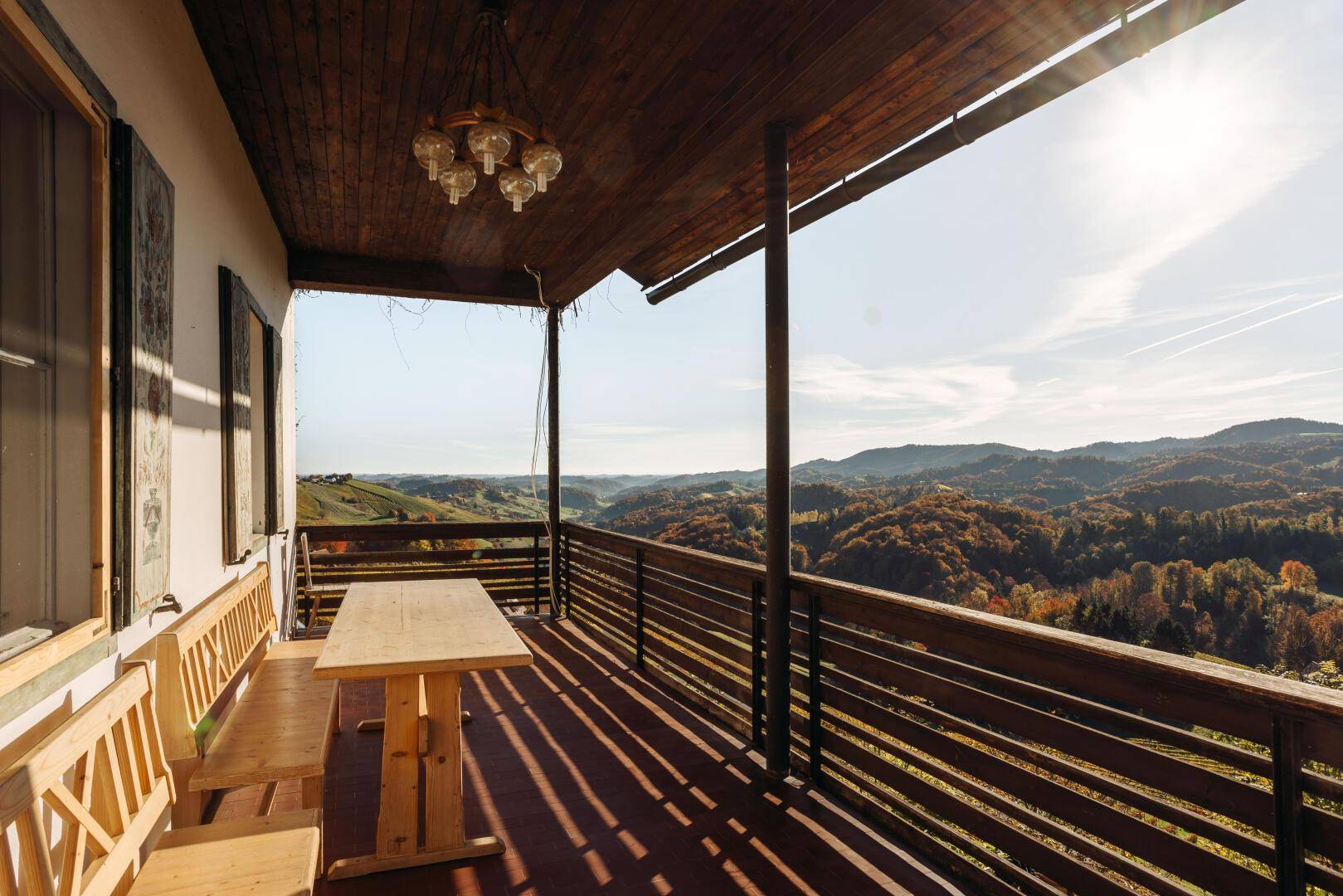 Gemütliche Loggia mit Holzbänken und Tisch, ideal für Mahlzeiten im Freien mit Aussicht.