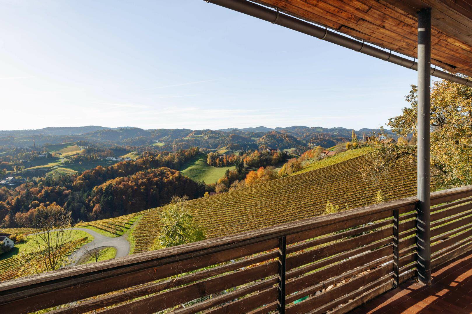 Loggia mit Holzboden und Geländer, die einen weiten Blick über die hügelige Landschaft bietet.