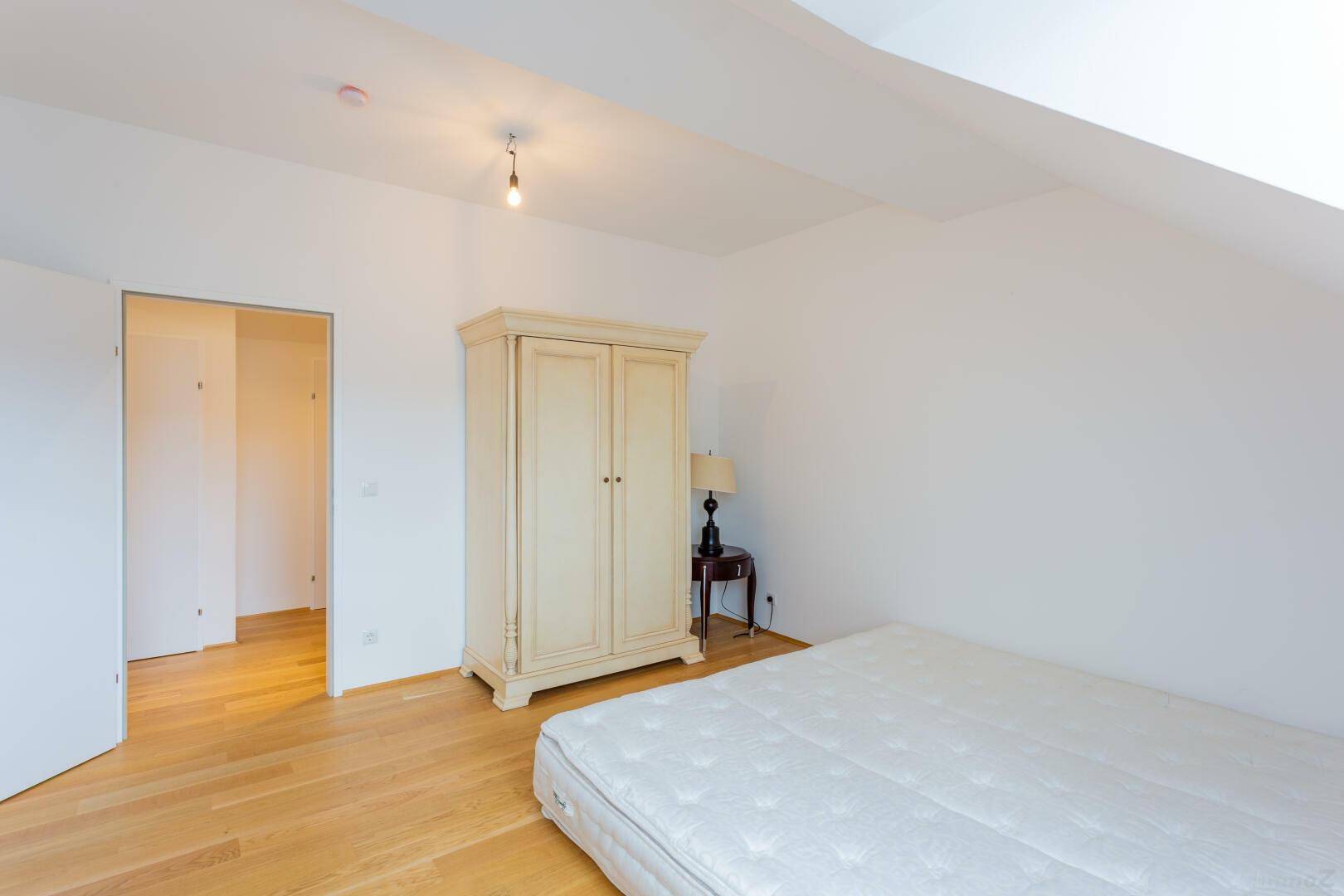 Geräumiges Schlafzimmer im Dachgeschoss mit hellem Parkettboden und großem Kleiderschrank.