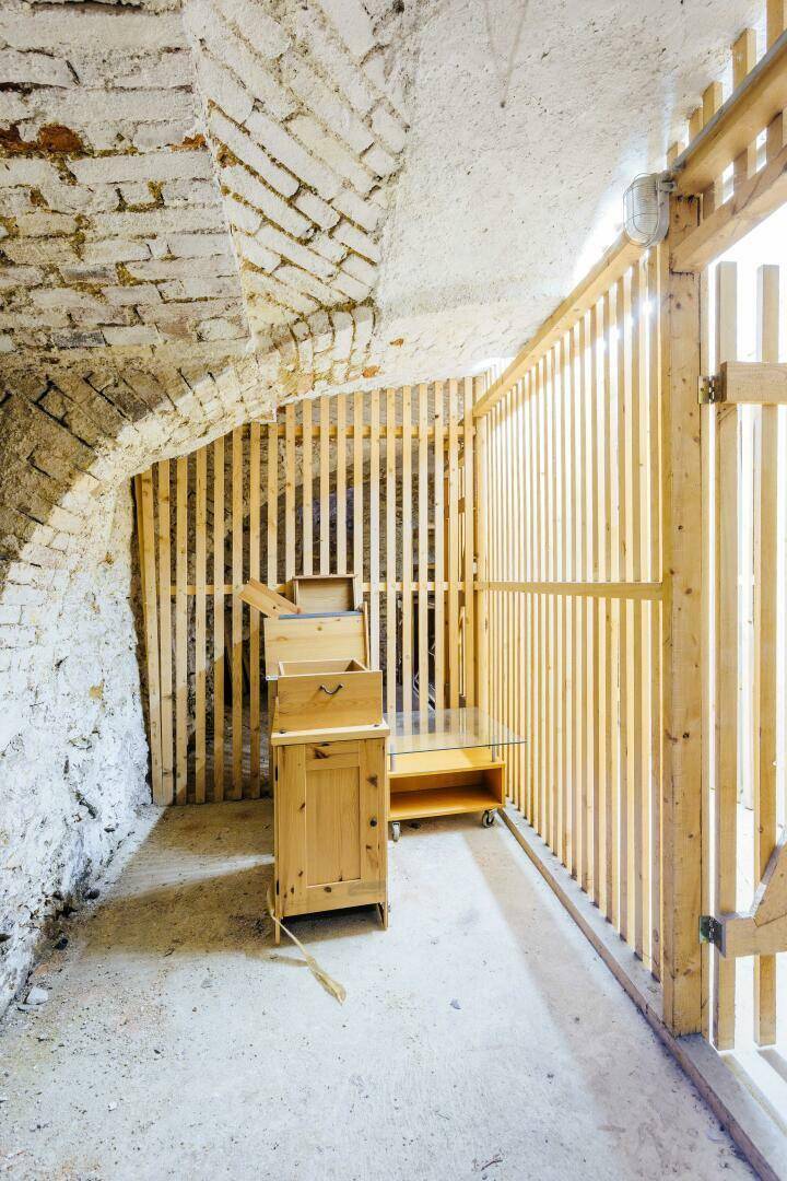 Rustikaler Kellerraum mit Ziegelwänden, Gewölbedecke und Holzabtrennungen für Lagerzwecke.