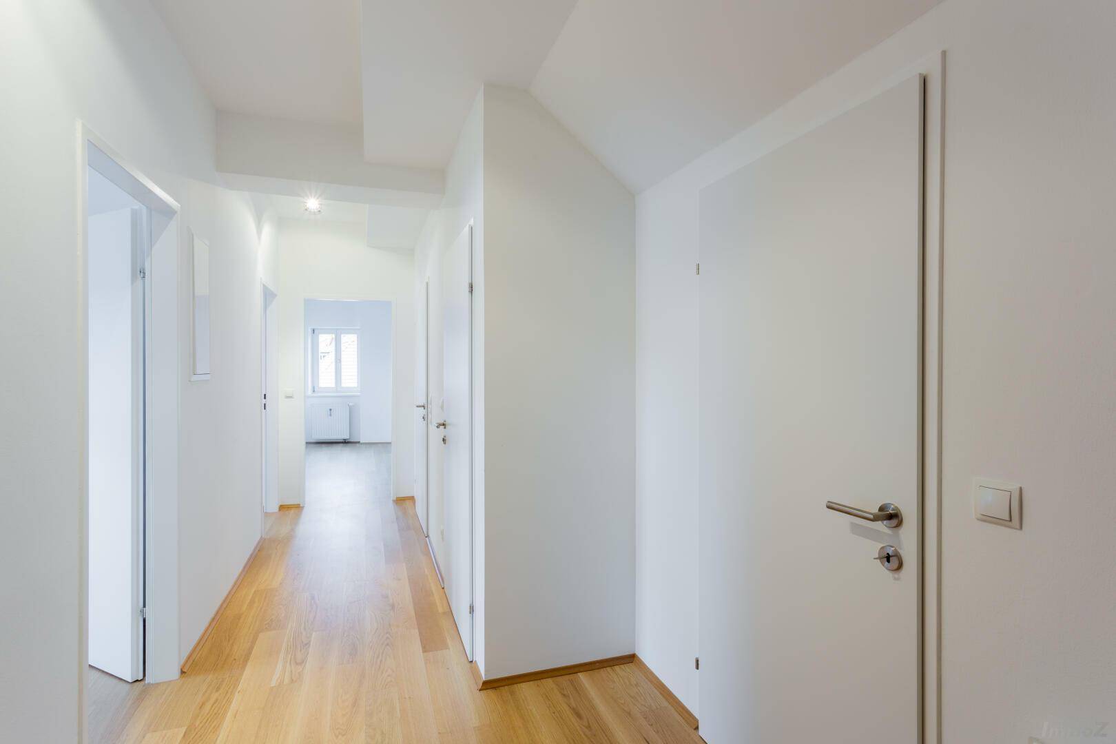Heller Flur mit Parkettboden und mehreren weißen Türen, die zu den Zimmern führen.