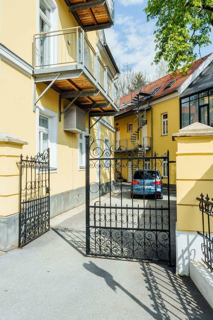 Einfahrt zum Innenhof mit schmiedeeisernem Tor und Blick auf die Gebäude.
