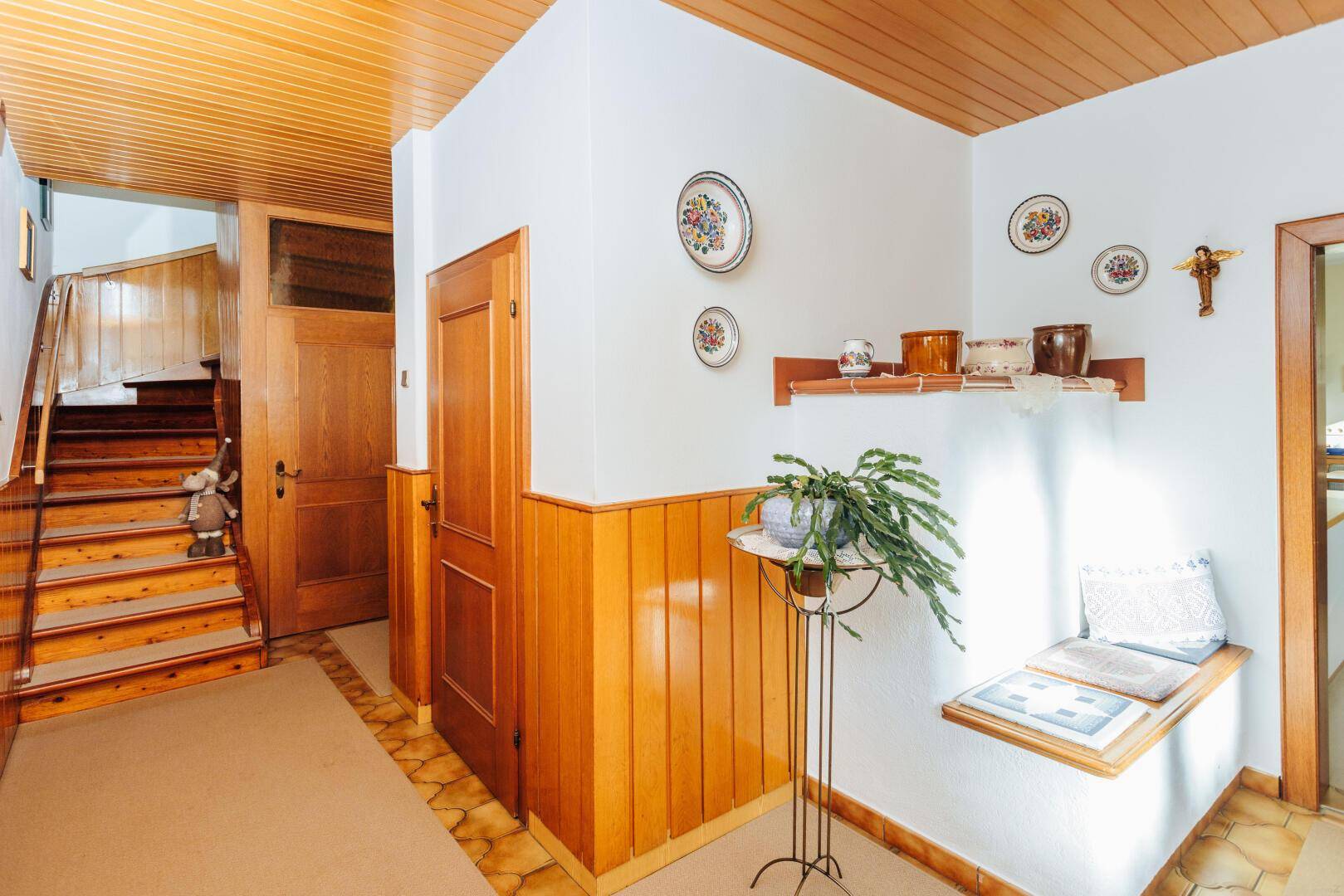 Flur mit Holztreppe, Holzvertäfelung und traditioneller Dekoration.