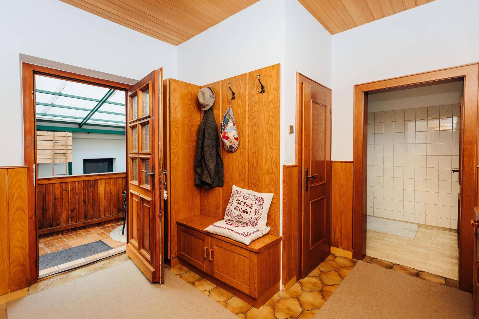Eingangsbereich mit Holzvertäfelung, Garderobe und Zugang zu weiteren Räumen.