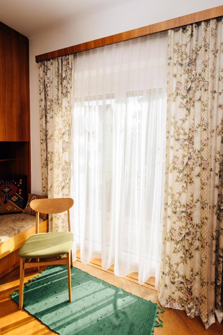 Fenster mit floralen Vorhängen und Blick nach draußen.