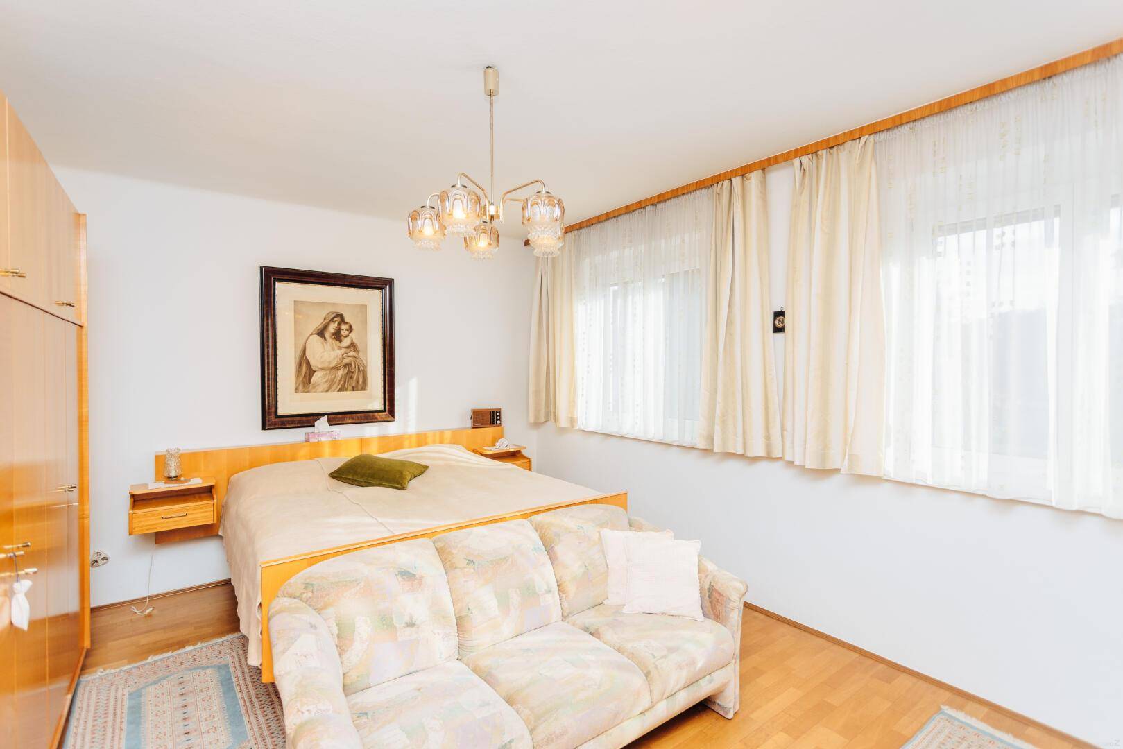 Schlafzimmer mit Doppelbett, Sofa und Holzschränken.