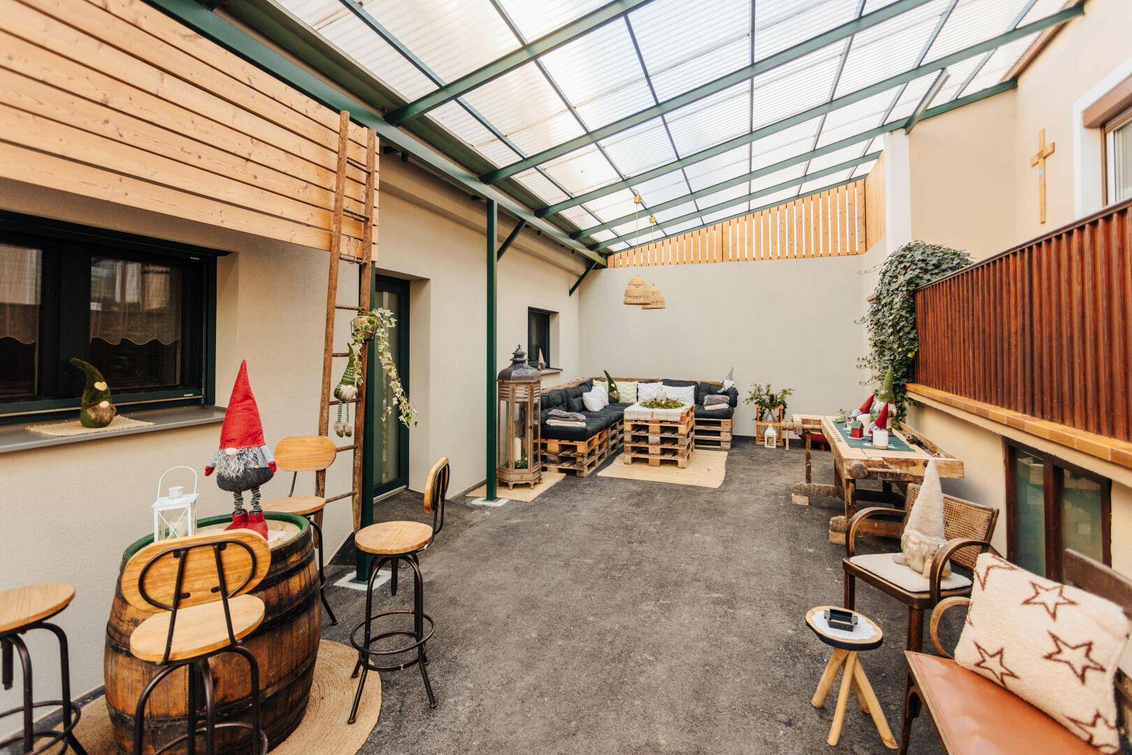 Überdachte Terrasse mit Palettenmöbeln, Holzelementen und Gartenzwerg.