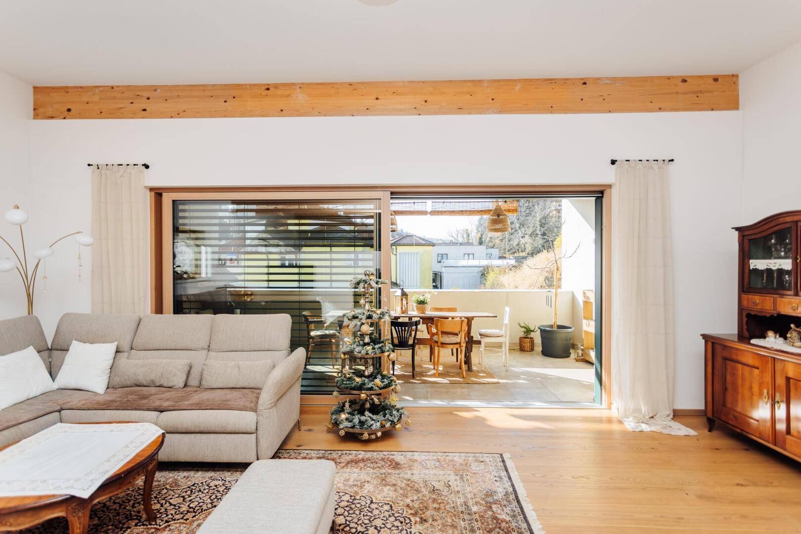Helles Wohnzimmer mit Sofa und großem Schiebefenster zum Balkon.