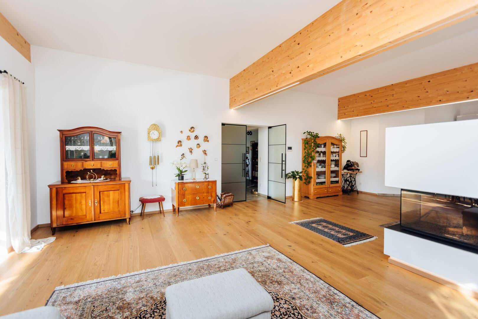 Geräumiges Wohnzimmer mit Holzboden, Kamin und traditionellen Möbeln.